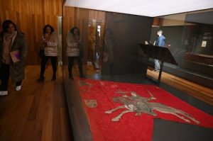 Visitantes contemplan el pendón de San Isidoro, extendido en una vitrina especial para su exposición.
